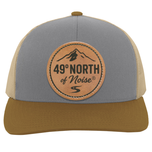 49° North trucker hat with Flathead River scout map leather patch – mid-profile cotton front and mesh back snapback, photographed outdoors on rustic wood table